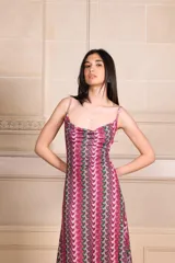 Vestido midi con estampado de ondas verticales en tonos fucsia, verde y plateado. Tiene breteles finos, escote drapeado y espalda baja.