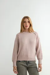 Buzo de tejido de punto en color rosado, con cuello redondo, mangas largas y puños acanalados. Presenta un diseño de tejido texturizado en la parte inferior y en los puños.