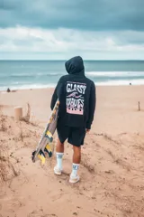 Hoodie negro de corte oversize, con capucha y estampa gráfica en la espalda con la inscripción "GLASSY WAVES" en tonos blancos y rosados.