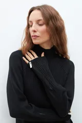 Polera de punto color ladrillo, de cuello alto y mangas largas con cierre en los puños.