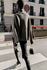 Jersey de punto color marrón oscuro con lentejuelas plateadas, cuello barco y manga larga acampanada.