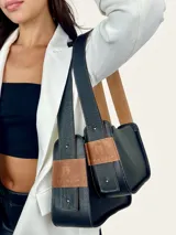 Bolso baguette de cuero negro con asa reversible y logo de la marca en etiqueta de cuero marrón.
