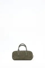Cartera tipo satchel de diseño rectangular, confeccionada en gamuza color verde oliva. Cuenta con doble asa corta de mano, cierre superior con cremallera metálica y logo de la marca grabado en el frente.