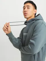 Canguro de manga larga color verde oscuro, con capucha ajustable mediante cordones, bolsillo tipo canguro y estampado en relieve con la frase "Originals Studio".