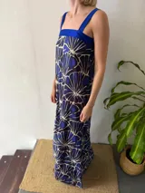 Vestido azul con estampado abstracto en blanco y azul oscuro. Presenta un escote cuadrado, tirantes anchos y un aplique de tafeta azul en el escote.