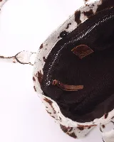 Cartera tipo baguette confeccionada en cuero vacuno con pelo y estampado animal print de vaca. Presenta doble asa de hombro, cierre superior y broches laterales para ajustar su volumen.
