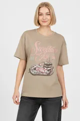 Remera de algodón color tostado, de manga corta, con cuello redondo y diseño holgado. Presenta una estampa frontal con la frase "Sweetness and Joy" en tonos rosados y una ilustración de postres.