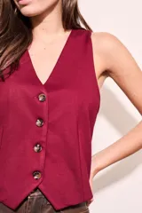 Chaleco color borgoña con escote en V y cierre frontal con botones.