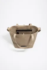 Bolso shopper mediano de tejido de punto color beige, con doble asa corta de mano y una correa larga ajustable para el hombro. Incluye parche con logo en la parte frontal.