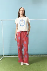 Pantalón de algodón color rojo con estampado de soles en color azul, de corte recto y cintura elástica con cordón ajustable.