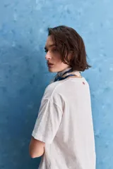 Remera negra de calce amplio, confeccionada en algodón liviano, con cuello redondo, mangas cortas y hombros levemente caídos.