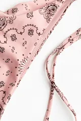 Vedetina de bikini rosa con estampado paisley en tonos negros y blancos, tiro medio y tiras ajustables para atar en los laterales.