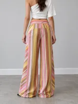 Pantalón de vestir de corte ancho y relajado, con estampa de rayas verticales en tonos rosados, amarillos y marrones.