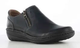 Zapato casual de mujer color negro, confeccionado en cuero, con cierre lateral y costuras decorativas visibles. Presenta una suela de goma robusta con detalle de pespunte en el borde.