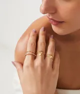 Set de seis anillos dorados con diferentes diseños: uno con dije de estrella, uno con forma de corazón, uno con strass, uno trenzado y dos con texturas.