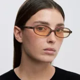 Lentes de sol con montura ovalada de color camel y cristales amarillos. Presentan un diseño estilizado y ligero, con protección UV400.