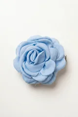 Broche para el pelo con diseño de flor de tela en color celeste, con clip metálico en la parte posterior.