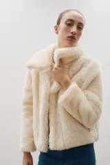 Campera corta de piel sintética en color crema, con cuello amplio tipo solapa y cierre frontal.