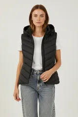 Chaleco acolchado negro con costuras horizontales, cierre frontal y capucha fija.