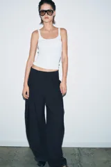 Pantalón de tiro medio con diseño wide leg, confeccionado en mezcla de lyocell. Presenta detalle de pinzas en el delantero, cierre frontal con cremallera, botón y ganchos metálicos.