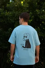 Remera celeste de manga corta con estampa en la espalda de un perro con gafas de sol tomando una copa y la palabra 'MOOD'.