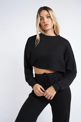 Buzo corto de tejido rib en color verde militar, con mangas largas y cuello redondo. Presenta un diseño holgado y cropped.