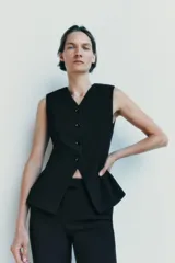 Chaleco negro entallado de Zara Woman Collection, con escote pico, sin mangas, forro interior a tono, bajo asimétrico y cierre frontal con botones.