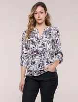 Blusa de gasa Zac & Rachel con estampado floral en tonos grises, negros y detalles fucsias sobre fondo blanco. Presenta cuello a la base con escote en V y botones frontales, y mangas largas con sistema de ajuste mediante presilla.