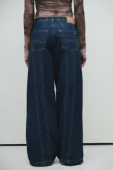 Pantalón de jean azul oscuro de pierna ancha con costuras marcadas al frente, tiro medio y calce relajado.