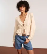 Blusa color crema con escote en V, mangas largas y lazo en el busto.