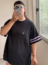 Remerón negro de algodón con mangas cortas y detalle de dos cintas de terciopelo lilas en cada manga.