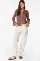 Blusa de lino italiano color beige con escote en V y detalles de volados en el cuello y los puños. Presenta cierre frontal con botones de nácar y mangas largas.