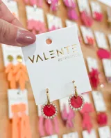 Aros colgantes con forma circular, color rojo con borde de strass plateado y gancho dorado. El material del aro es de acero.