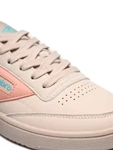 Championes Umbro modelo Rian, de diseño clásico en color blanco con detalles en rosado en el talón y logo lateral. Presentan suela de goma en tono crema y perforaciones en la puntera para mayor ventilación.