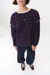 Remera de manga larga con corte oversized, color azul marino con cuello redondo en contraste color marrón. Presenta costuras decorativas a contratono hechas a mano en la zona de los hombros y logo bordado en el centro del pecho.