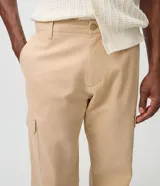Pantalón cargo de corte recto en color beige, confeccionado en tejido de sarga de algodón. Cuenta con bolsillos laterales y bolsillos cargo con solapa en las piernas, cintura con pasacintos y cierre frontal con botón y cremallera.
