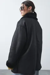 Tapado de efecto cuero negro con interior y detalles de cuello y puños en pelo sintético. Presenta un diseño envolvente con cierre frontal de botones y bolsillos laterales.