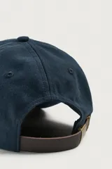 Gorra de seis paneles azul marino confeccionada en tejido de algodón, con bordado frontal en tono contrastante con la leyenda "button 84".