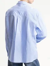 Camisa de corte clásico con estampado de rayas verticales en tonos beige y blanco. Presenta cuello camisero, cierre frontal con botones y corbata integrada del mismo tejido y estampado.