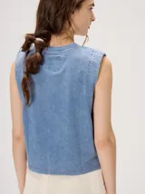 Musculosa crop de algodón con efecto acid wash en color lila, cuello redondo, hombreras marcadas y pequeño bordado central en el pecho.