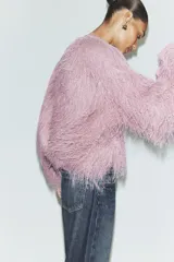 Chaqueta bomber de cuello redondo y manga larga, confeccionada con un acabado de flecos largos en toda la prenda. Presenta cierre frontal con corchetes y puños elásticos.
