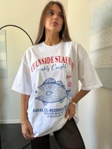 Remerón oversize color fucsia con estampa de pescado y texto en azul.