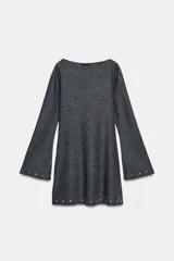 Vestido corto de punto color gris oscuro, con cuello barco y mangas largas acampanadas. Presenta detalles de tachas metálicas aplicadas en el ruedo y en los puños, con un diseño de corte evasé.