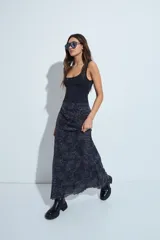 Falda larga de corte fluido con estampado de cuadros en tonos oscuros, rojizos y blancos. Presenta un diseño ligero con terminaciones onduladas en el ruedo.