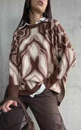 Sweater de tejido de punto con diseño estampado abstracto en tonos marrones y beige, de corte oversize, cuello redondo y mangas largas con puños acanalados.