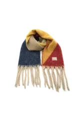 Bufanda de tejido suave con diseño de bloques de color en tonos azul, amarillo y rojo, terminada con flecos largos en color beige. Incluye una etiqueta decorativa con la marca Trendy.