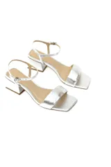 Sandalias de tacón medio color plateado, confeccionadas en cuero genuino. Presentan una tira ancha en la parte delantera, pulsera fina ajustable al tobillo y tacón bloque de aproximadamente 6 cm.