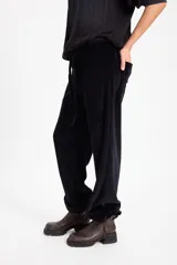 Pantalon de tiro bajo con diseño híbrido que combina elementos formales y deportivos. Presenta cintura y bajos ajustables, con elástico en la parte trasera de la pretina interna.