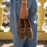 Mocasines de cuero color tostado, con punta cuadrada, costuras artesanales visibles y suela plana de goma.