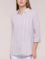 Camisa de lino de la marca Dash, color beige con rayas verticales blancas. Cuenta con cuello camisero, cierre frontal con botones, un bolsillo aplicado en el pecho y mangas largas con sistema de ajuste para arremangar.
